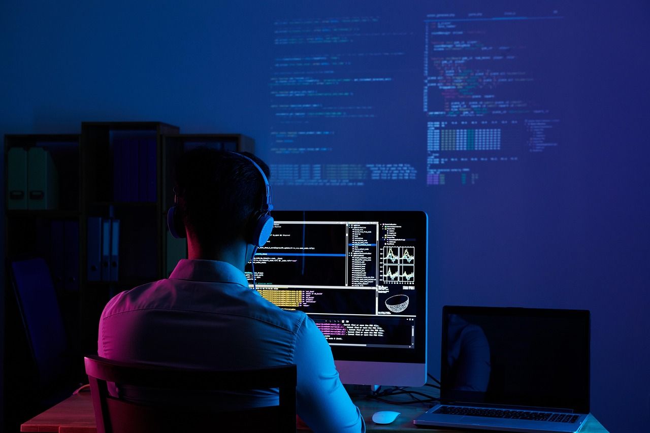 Entwickler an einem Arbeitsplatz mit mehreren Bildschirmen voller Programmcode