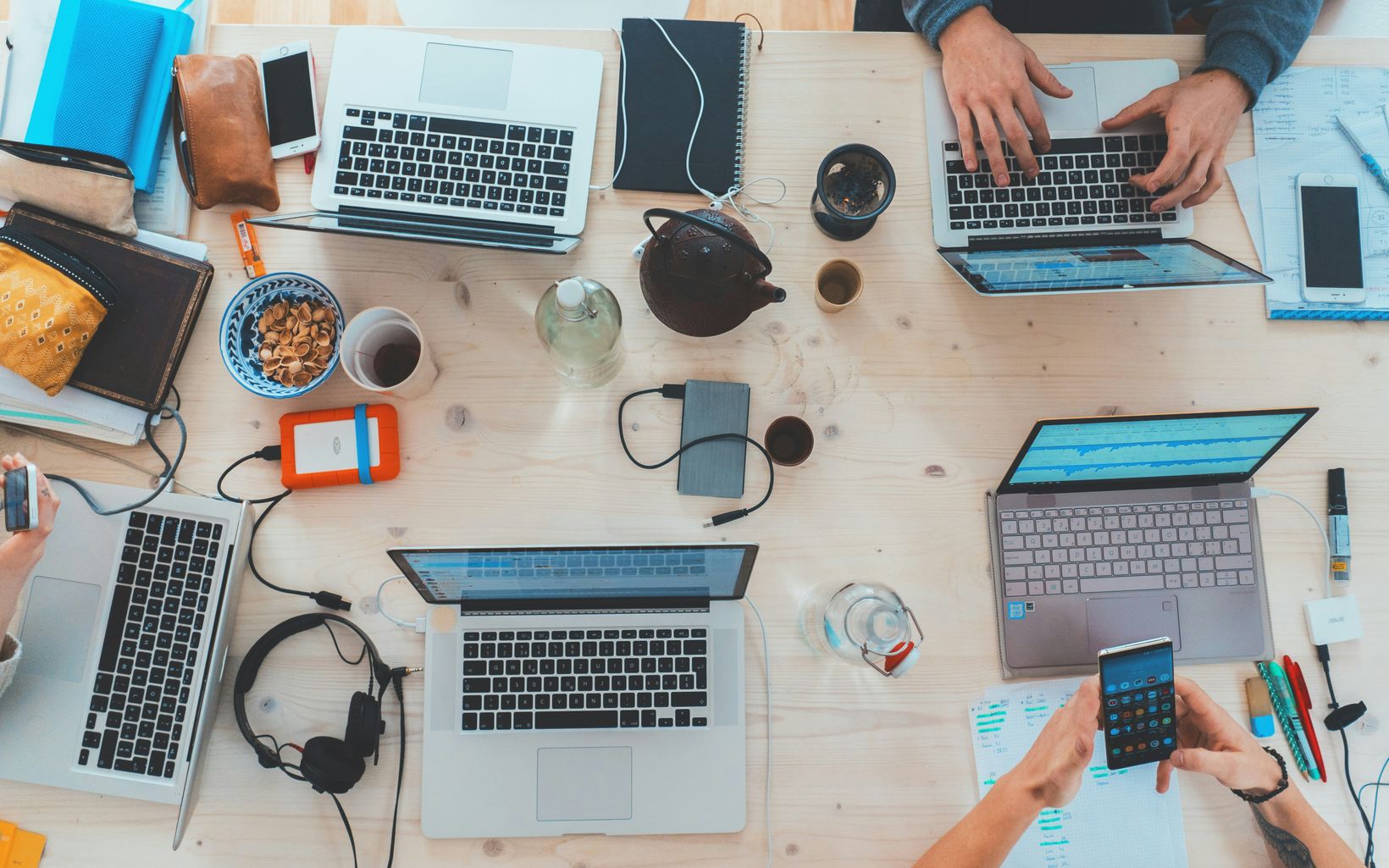 Top view of a meeting table with several laptops and notes